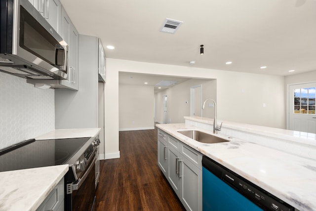 kitchen with sink, gray cabinetry, stainless steel appliances, dark hardwood / wood-style floors, and light stone countertops