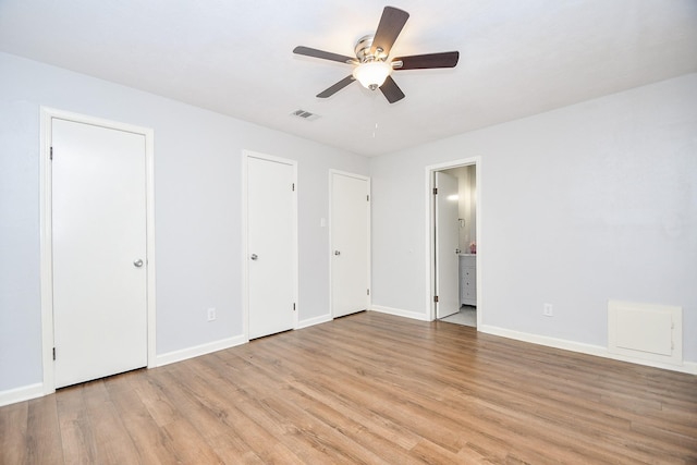 unfurnished bedroom featuring multiple closets, connected bathroom, ceiling fan, and light hardwood / wood-style flooring