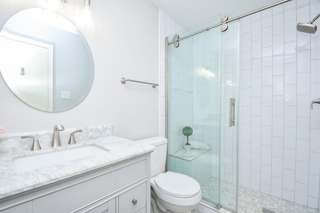 bathroom featuring a shower with door, vanity, and toilet