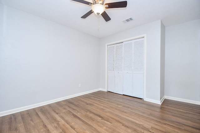 unfurnished bedroom with hardwood / wood-style flooring, ceiling fan, and a closet