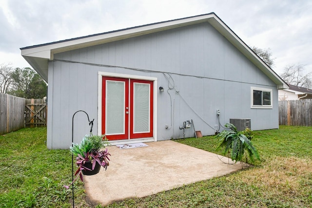 rear view of property with french doors, a patio, central air condition unit, and a lawn