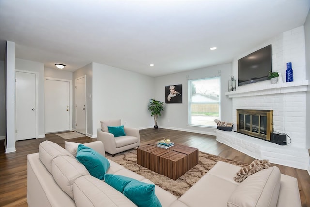 living room with a brick fireplace and hardwood / wood-style floors