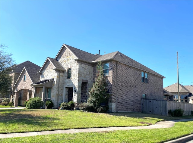 exterior space with a yard, stone siding, brick siding, and fence