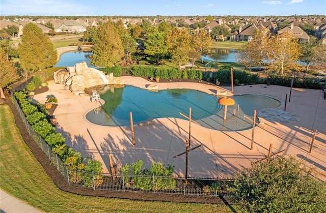 view of swimming pool with a water view, a water slide, a patio, and fence