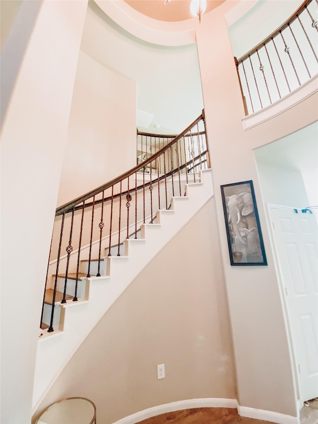 staircase featuring a high ceiling and baseboards