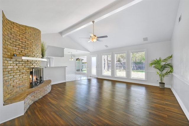 living room featuring dark wood-type flooring, a fireplace, beam ceiling, and a wealth of natural light