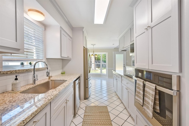 kitchen with sink, light stone counters, tasteful backsplash, stainless steel appliances, and white cabinets