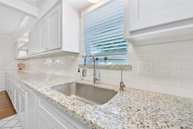 kitchen featuring white cabinetry, sink, crown molding, and light stone countertops