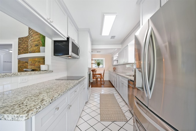 kitchen with tasteful backsplash, stainless steel appliances, light tile patterned floors, and white cabinets