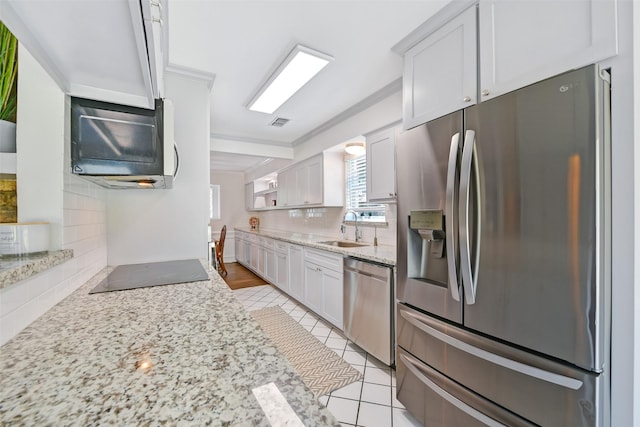 kitchen featuring appliances with stainless steel finishes, tasteful backsplash, white cabinetry, sink, and light stone countertops