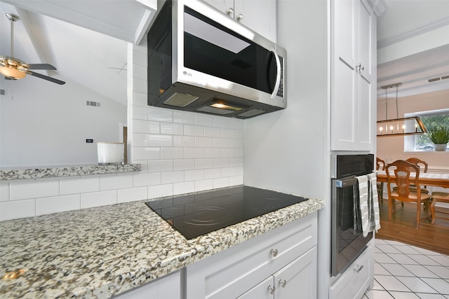 kitchen with stainless steel appliances, light stone counters, tasteful backsplash, white cabinets, and ceiling fan with notable chandelier