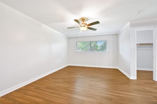 unfurnished bedroom with crown molding, a walk in closet, ceiling fan, and light hardwood / wood-style flooring