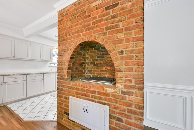 kitchen with crown molding, light stone countertops, light hardwood / wood-style floors, and white cabinets