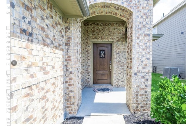 property entrance featuring brick siding, stone siding, and cooling unit