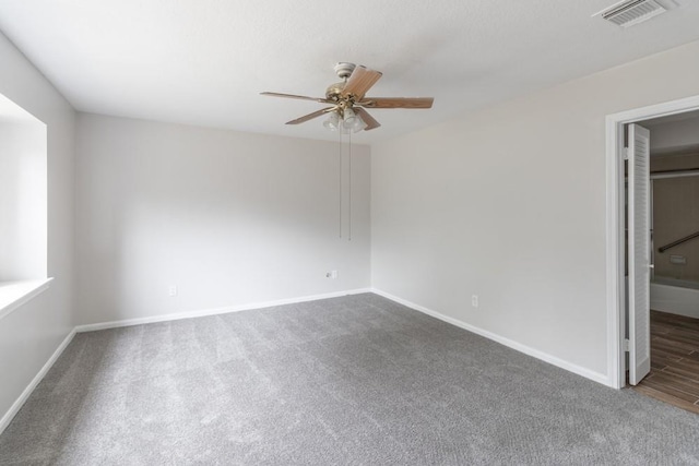 empty room with ceiling fan and dark colored carpet