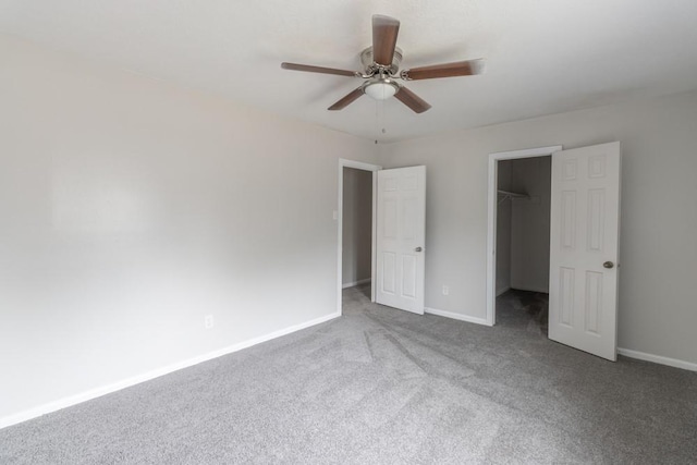 unfurnished bedroom featuring carpet floors, a spacious closet, ceiling fan, and a closet