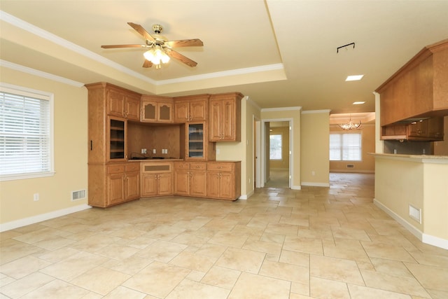 kitchen featuring ornamental molding, ceiling fan with notable chandelier, and a tray ceiling