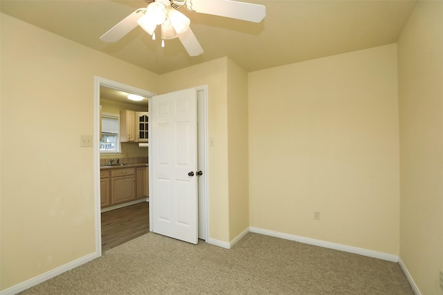 unfurnished bedroom featuring ceiling fan, sink, and light carpet