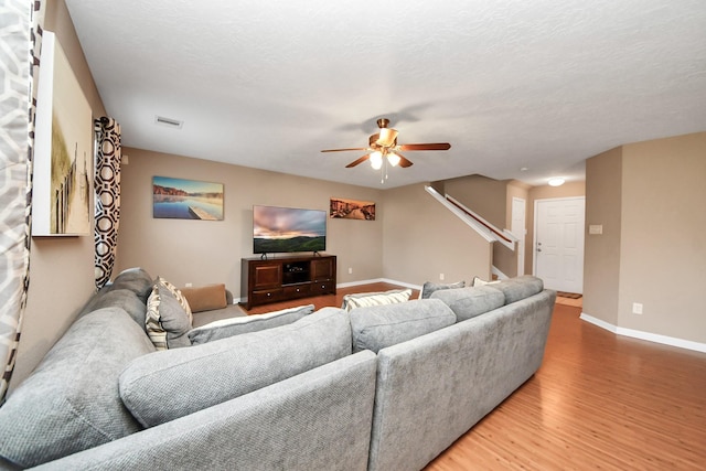 living room featuring wood-type flooring, a textured ceiling, and ceiling fan