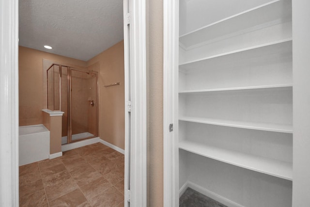 bathroom featuring independent shower and bath and a textured ceiling