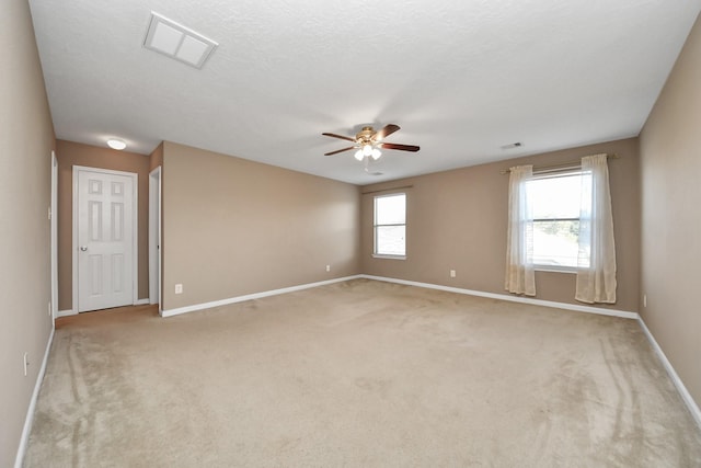 empty room featuring ceiling fan, light colored carpet, and a textured ceiling