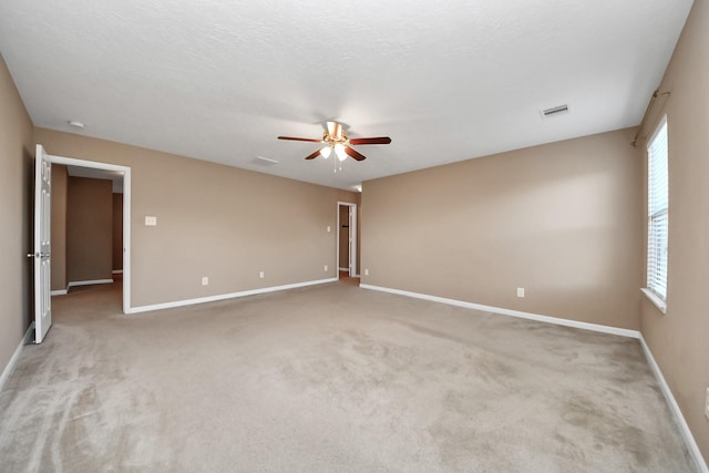 empty room with ceiling fan, light carpet, and a textured ceiling