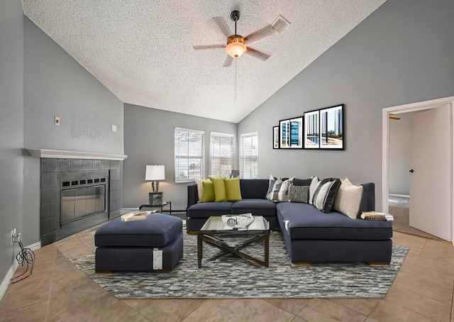 tiled living room featuring a tiled fireplace, a textured ceiling, high vaulted ceiling, and ceiling fan