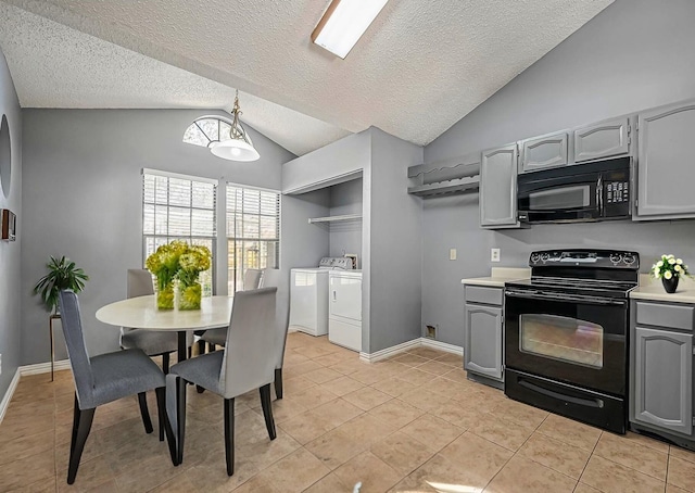 kitchen featuring gray cabinetry, washing machine and clothes dryer, hanging light fixtures, and black appliances