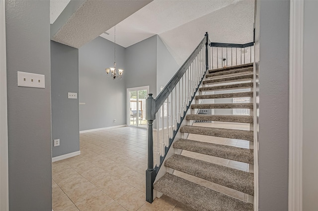 staircase with an inviting chandelier, a towering ceiling, tile patterned floors, and a textured ceiling