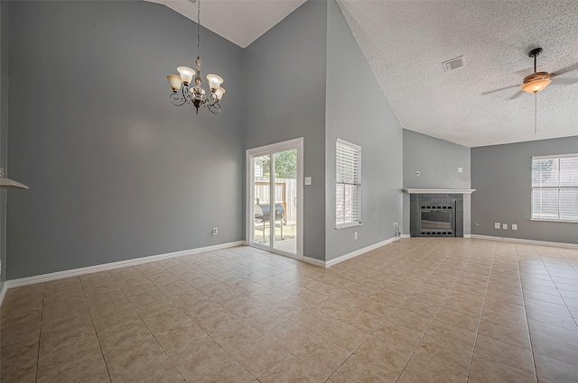 unfurnished living room featuring a tiled fireplace, light tile patterned floors, ceiling fan with notable chandelier, and a healthy amount of sunlight