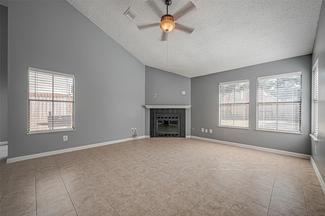 unfurnished living room featuring light tile patterned flooring, a tiled fireplace, vaulted ceiling, and a wealth of natural light