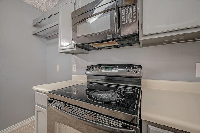 kitchen with white cabinetry, light tile patterned floors, and black appliances