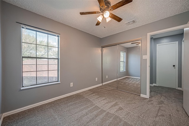 unfurnished bedroom featuring ceiling fan, a closet, carpet flooring, and a textured ceiling