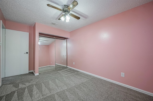 unfurnished bedroom with ceiling fan, a closet, a textured ceiling, and dark colored carpet