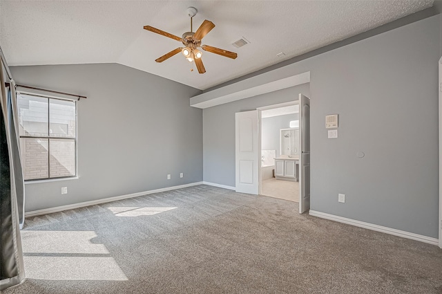 unfurnished bedroom featuring lofted ceiling, carpet flooring, a textured ceiling, and ensuite bath