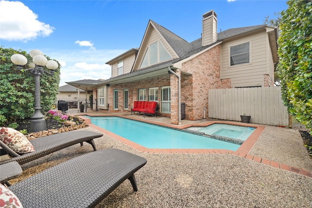 rear view of property with a patio and a pool with hot tub