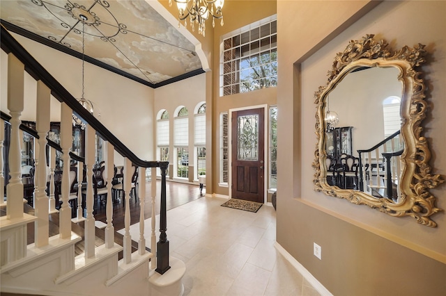 entryway featuring a high ceiling, ornamental molding, and a chandelier