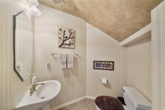 bathroom with tile patterned flooring, lofted ceiling, sink, and toilet