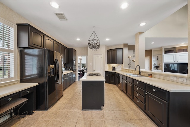 kitchen with a healthy amount of sunlight, a center island, sink, and black refrigerator with ice dispenser