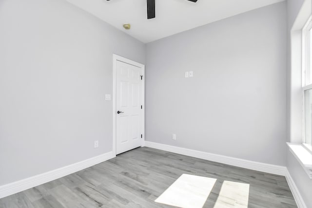 spare room with a wealth of natural light, ceiling fan, and light wood-type flooring