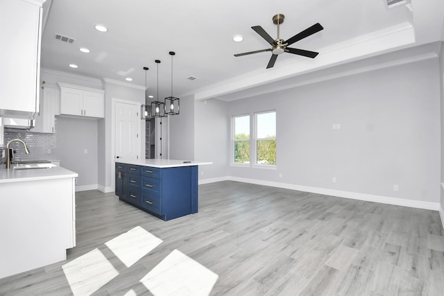 kitchen featuring pendant lighting, sink, blue cabinets, white cabinets, and a kitchen island