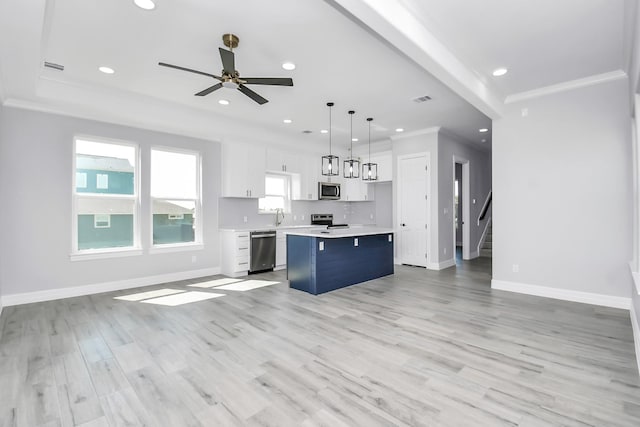 kitchen featuring decorative light fixtures, white cabinetry, a center island, stainless steel appliances, and crown molding