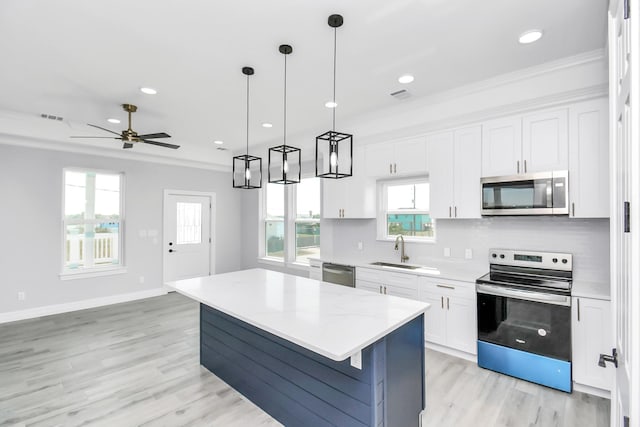 kitchen with pendant lighting, sink, stainless steel appliances, a center island, and white cabinets