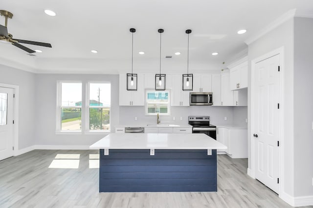 kitchen featuring sink, appliances with stainless steel finishes, white cabinetry, hanging light fixtures, and a center island