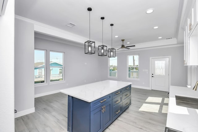 kitchen with sink, white cabinets, a kitchen island, decorative light fixtures, and a raised ceiling