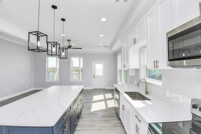 kitchen with decorative light fixtures, stainless steel appliances, a center island, and white cabinets