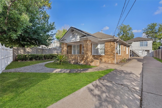 bungalow-style home with fence, a front lawn, driveway, and brick siding