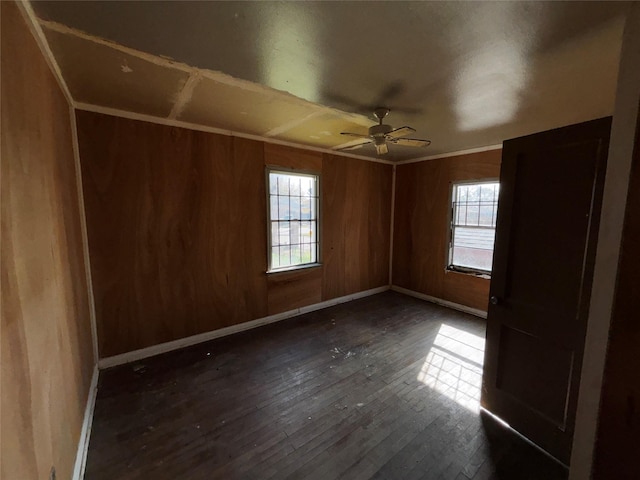 unfurnished room featuring ceiling fan, wooden walls, ornamental molding, and dark hardwood / wood-style floors