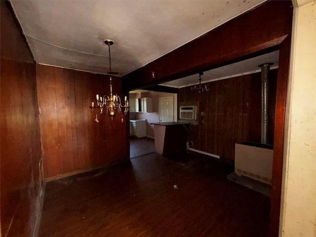 unfurnished dining area featuring an inviting chandelier, wooden walls, dark hardwood / wood-style flooring, a wall unit AC, and beamed ceiling