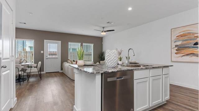 kitchen featuring white cabinetry, sink, dark stone countertops, stainless steel dishwasher, and a center island with sink